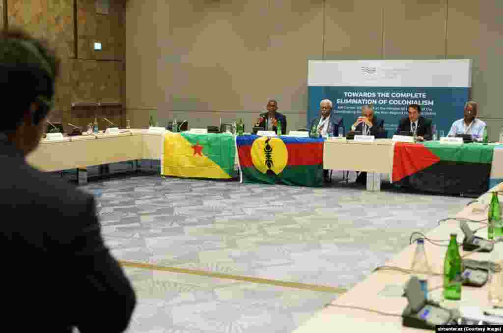 Azerbaijani flags began appearing in New Caledonia soon after political activists from several French territories were flown to Baku for a conference, called Towards The Complete Elimination Of Colonialism, in July 2023.&nbsp; In this photo from the event, speakers sit behind flags used in the French territories of (left to right) French Guiana, New Caledonia, and Martinique.&nbsp; &nbsp;