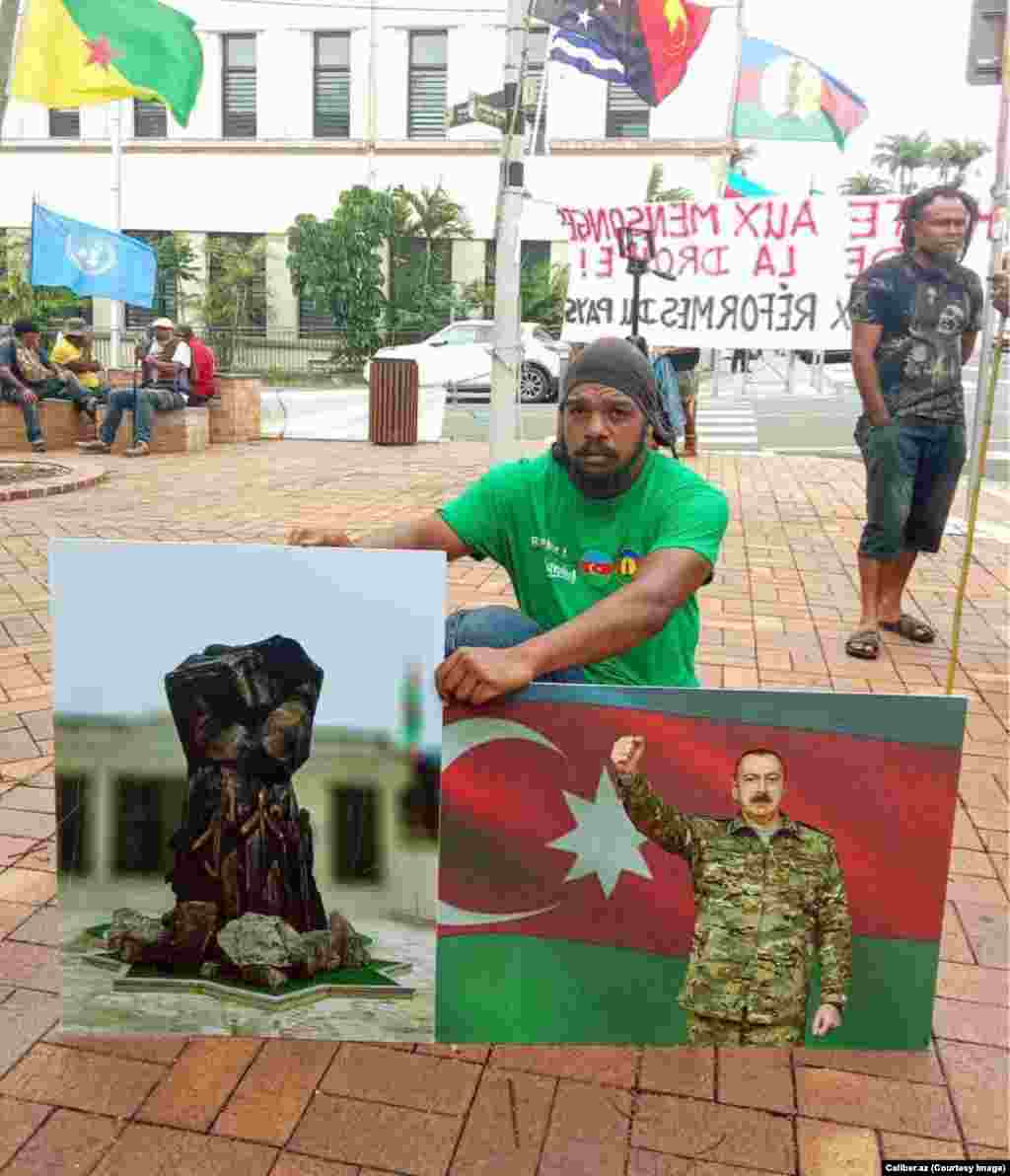 A protester in Noumea is photographed in March holding pictures of Azerbaijani President Ilham Aliyev and of an Azerbaijani war memorial. The pictured memorial&nbsp;was recently unveiled in Azerbaijan&#39;s retaken Kalbacar district. &nbsp;