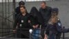 The suspect in the shooting, his head covered by a coat, is escorted by police outside the Vladislav Ribnikar Elementary School in Belgrade on May 3.