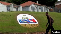 A man walks past a floral display announcing the 5th BRICS summit in Durban, South Africa.