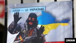 Плакат із зображенням Володимира Путіна у вигляді «зеленого чоловічка» під час акції «Крим – це Україна» біля російського посольства у Києві, 16 березня 2020 року