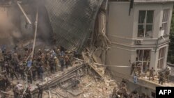 Співробітники екстреної та рятувальної служби разом із медиками та іншими людьми розчищають завали зруйнованої будівлі дитячої лікарні «Охматдит» після російського ракетного удару у Києві, 8 липня 2024 року 
