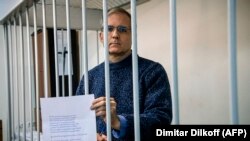 Paul Whelan holds up a message as he stands inside a defendants' cage before a hearing to decide to extend his detention at a court in Moscow on October 24.
