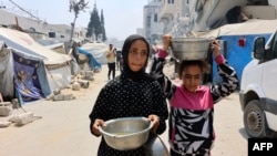 Raseljeni Palestinci nose lonce supe od leće koju su dobili na punktu za distribuciju hrane u gradu Gazi, 25. jula 2025.