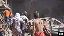 People flee the site of a bombing in the Kurdish city of Qamishli, near the Turkish border on July 27.