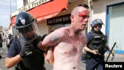 An injured man is led away by French police in Marseille following clashes between Russia and England supporters after a 1-1 draw in Marseille on June 11.