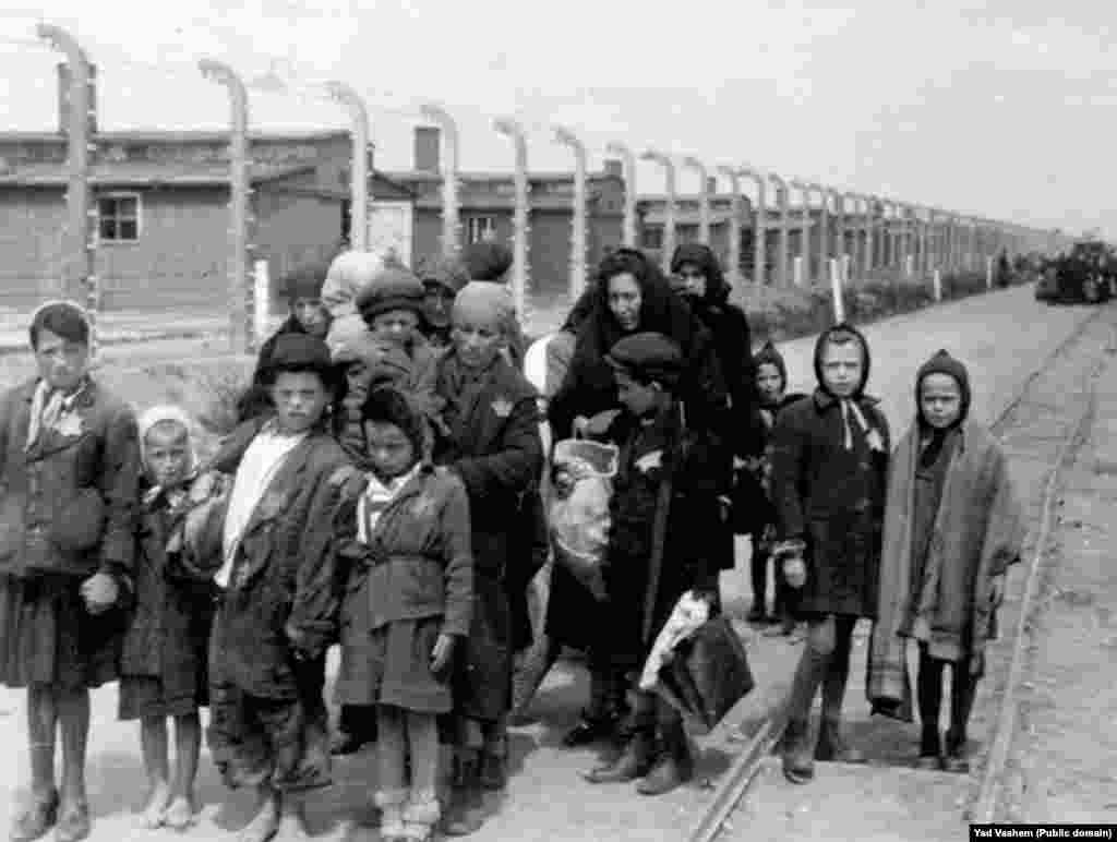 На фото справа: 1944 год. Женщина с детьми направляется в газовую камеру. На заднем фоне видны деревянные бараки &ndash; это лагеря Биркенау, дополнительно построенные в Освенциме. После войны здания были разрушены, но кирпичные стены и дымоходы сохранились.