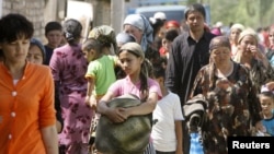 Ethnic Uzbeks carry belongings as they return to the southern Kyrgyz city of Osh from Uzbekistan shortly after the June violence.