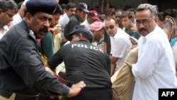 Pakistani security officials carry the bodies of two Christians killed outside a court in Faisalabad on July 19.