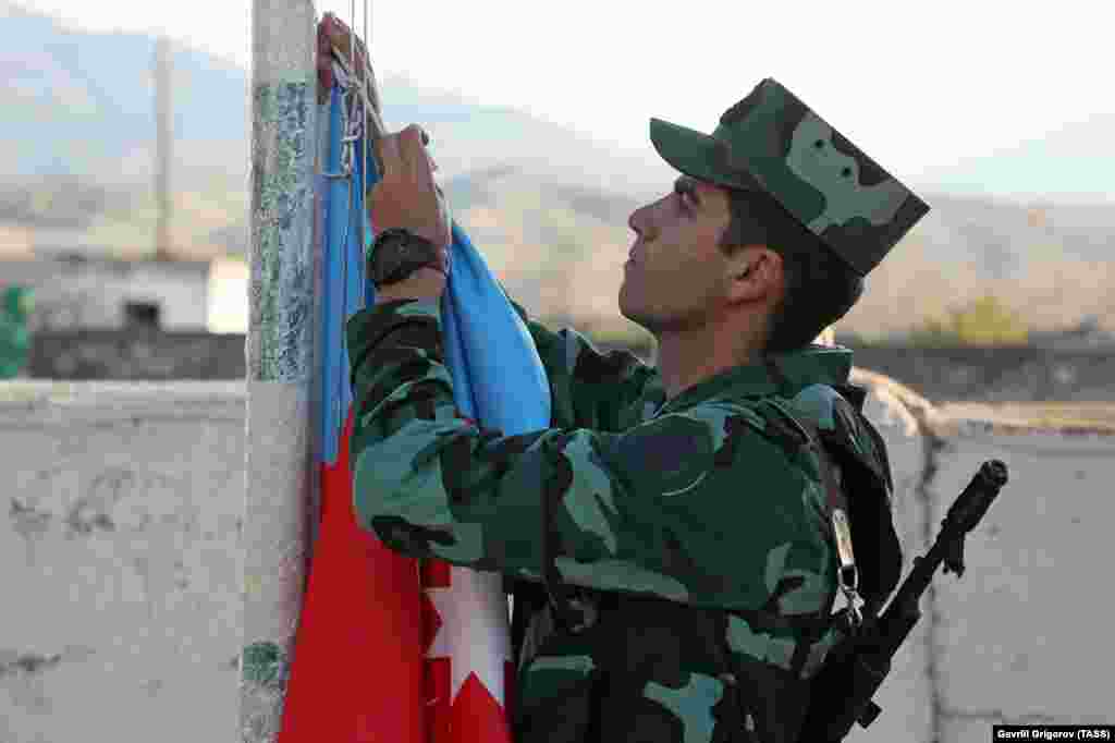 An Azerbaijani soldier hoists his country&#39;s flag during a ceremony in the village of Mincivan, which was recently taken from Armenian forces.&nbsp;