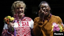 Claressa Shields (right) of the United States poses with her gold medal accompanied by silver medallist Nadezda Torlopova of Russia during the presentation ceremony for the women's middleweight boxing competition at the London Olympic Games on August 9. 