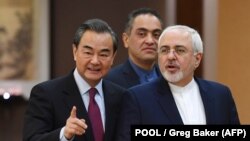 Iran's Foreign Minister Mohammad Javad Zarif (right) arrives with his Chinese counterpart, Wang Yi, for a joint press conference in Beijing on December 5, 2016.
