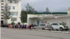 Люди сидят неподалеку от магазина в ожидании начала продажи продуктов питания. Государственный магазин №4 в 11-м микрорайоне Ашхабада. Май, 2021